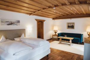 a bedroom with a white bed and a blue couch at Hotel Ziegleder in Rottach-Egern