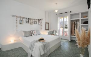 een witte slaapkamer met een wit bed met een hoed erop bij "Palatiana Agriturismo-Philoxenia Cottages", Private Nature Retreats in Galini