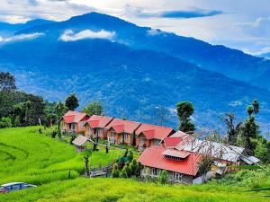 a group of houses on a hill with a mountain in the background at Chibbo Retreat - A Hamlet near Kalimpong by StayApart in Kalimpong