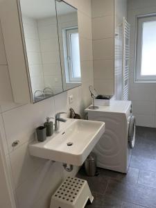 Baño blanco con lavabo y espejo en Ferienwohnung Edelbach Deluxe, en Sattendorf