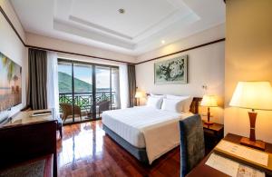 ニャチャンにあるVinpearl Resort Nha Trangのベッドと大きな窓があるホテルの部屋