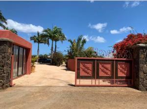 a gate in front of a building with palm trees at Super villa familiale in Pointe aux Piments