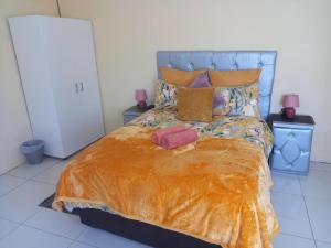 a bedroom with a bed with an orange blanket and pillows at Claytons accommodation in Bedford