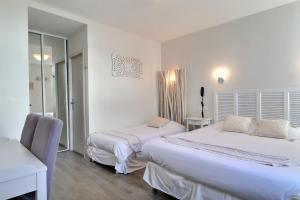 a bedroom with two beds and a desk and a mirror at Grand Hôtel des Bains SPA in Fouras