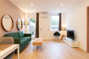 a living room with a green couch and a tv at LE 23 in Jarny