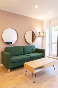 a living room with a green couch and two mirrors at LE 23 in Jarny