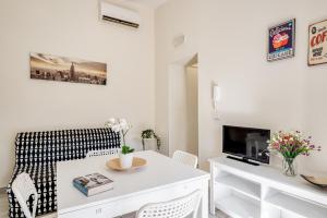 ein Wohnzimmer mit einem weißen Tisch und einem TV in der Unterkunft Catania Modern Beige Apartment in Catania