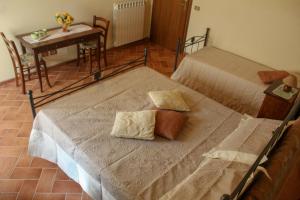 two beds in a room with a table and a tableablish at Agriturismo Colle Verde in Castelfalfi