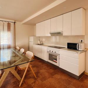 a kitchen with white cabinets and a glass table at El Escondite de La Caprichosa in Madrid