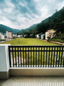 un balcón con vistas a un gran campo. en HOT - House Of Travellers en Rishīkesh