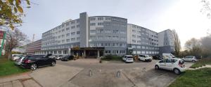 a large building with cars parked in a parking lot at R&B Hotel in Berlin