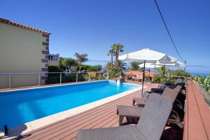 a swimming pool with chairs and an umbrella on a deck at Finca Marina BuenVivir in Tazacorte