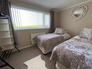 a bedroom with two beds and a mirror on the wall at Stunning Cottage in Holyhead in Holyhead