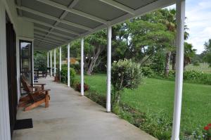 a covered porch with a bench and a lawn at Jacaranda Lodge in Coromandel Town