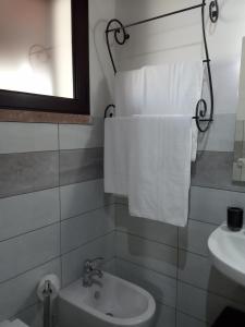een badkamer met een wastafel, een toilet en handdoeken bij Agriturismo Pedru Caddu in Tula