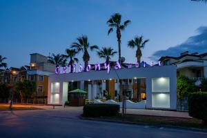 a building with a neon sign in front of it at Tu Casa Gelidonya Hotel in Kemer