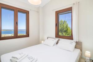 a bedroom with two beds and two windows at Seaview Villas in Vourvourou +49 photos
