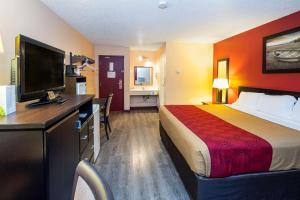 a hotel room with a bed and a flat screen tv at Econolodge Edson in Edson