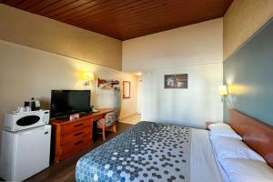 Econo Lodge Motel Village في كالغاري: غرفة فندقية بسرير وتلفزيون بشاشة مسطحة