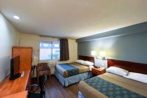 a hotel room with two beds and a desk at Econo Lodge Motel Village in Calgary