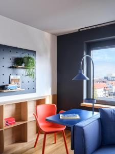 ein Wohnzimmer mit einem blauen Tisch und einem roten Stuhl in der Unterkunft STAYERY Wolfsburg City in Wolfsburg