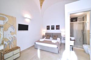 a white bedroom with a bed and a bathroom at L'Antica Rimessa Da Gigi in Gallipoli