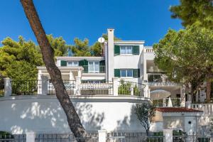 een groot wit huis met bomen ervoor bij Apartments Croatia in Trogir