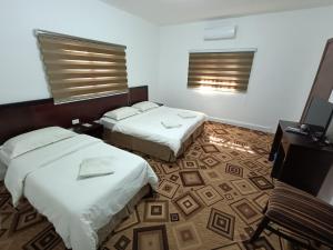 ein Hotelzimmer mit 2 Betten und einem Schreibtisch in der Unterkunft Happy Night Hostel in Wadi Musa