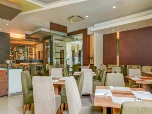 un restaurante con mesas de madera y sillas verdes en Townhouse OAK Hotel Grand Cikarang, en Cikarang