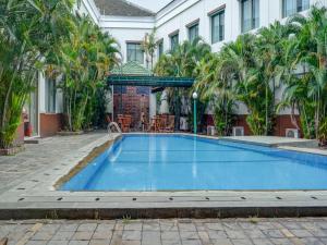 a pool in the courtyard of a hotel with palm trees at Townhouse OAK Hotel Grand Cikarang in Cikarang