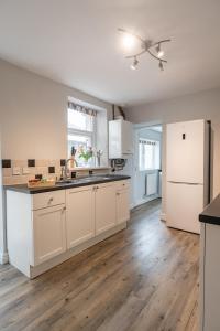 a kitchen with white cabinets and a hard wood floor at Seascape Cottage in Haverigg