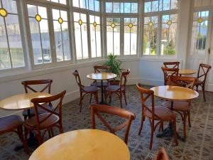 a room with tables and chairs and windows at HI Vila do Conde - Pousada de Juventude in Vila do Conde