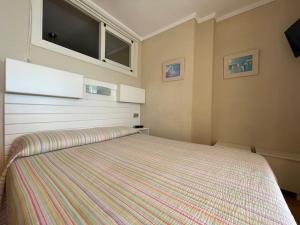 sypialnia z dużym łóżkiem i pasiastym kocem w obiekcie Apartamento Calma Chica w mieście Torremolinos