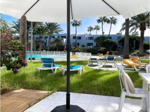 a patio with chairs and an umbrella and a pool at Los Barqueros 16 by Best Holidays Fuerteventura in Corralejo