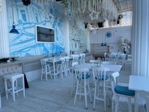 um restaurante com mesas e cadeiras brancas e uma televisão em Beautiful 1-Bed Apartment em Hurghada