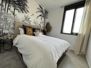 een slaapkamer met een bed met witte lakens en tropisch behang bij Outstanding 2 bed apartment with rooftop sea views in Mar de Cristal