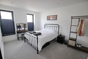 a bedroom with a bed and a desk and two windows at Modern Home for Small Groups by Stones Throw Apartments - Free Parking - Sea View in Worthing