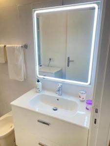 a white bathroom with a sink and a mirror at Lovely apartment with pool in Costa Del Silencio