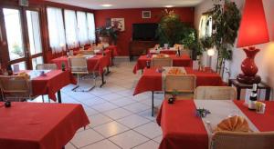 a restaurant with red tables and chairs with red tablecloths at Contact Hôtel Arc-En-Ciel - Réouverture - Rénové in Mulhouse