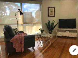 ein Wohnzimmer mit einem Sofa und einem Flachbild-TV in der Unterkunft Design/bright/cosy townhouse between airport &city in Melbourne