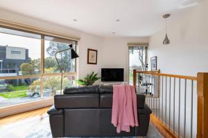 ein Wohnzimmer mit einem Ledersofa und einem TV in der Unterkunft Design/bright/cosy townhouse between airport &city in Melbourne