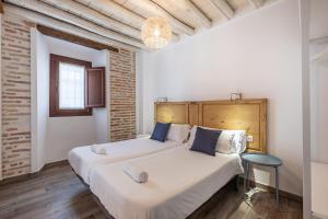Habitación con 2 camas, paredes blancas y suelo de madera. en Apartamentos Boutique Granada 3000, en Granada