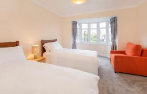 a bedroom with two beds and a orange chair at Peace house - 56 Sycamore Terrace in York