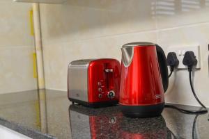 a red appliance sitting on a counter next to a toaster at Immaculate Villa in Gaborone