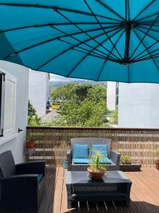a patio with two chairs and a blue umbrella at La Terrasse des manguiers in Saint-Denis