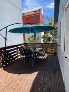 une table et des chaises sur une terrasse avec un parasol bleu dans l'établissement La Terrasse des manguiers, à Saint-Denis