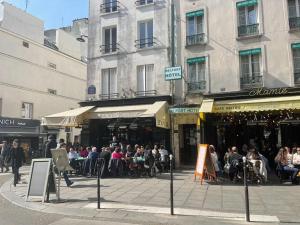 a group of people sitting at tables on a city street at charmant studio sous les toits de Paris in Paris