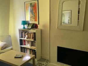 a living room with a tv and a book shelf with books at charmant studio sous les toits de Paris in Paris