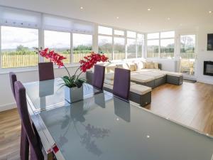a living room with a glass table and a couch at Top Of The Lane Luxury Holiday Apartment in Benllech