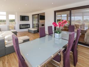 a dining room with a glass table and purple chairs at Top Of The Lane Luxury Holiday Apartment in Benllech
